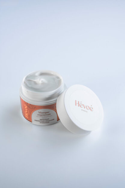 Texture onctueuse du Masque Régénérant Hévoé, pot ouvert devant son étui éco-conçu, prêt à l’application